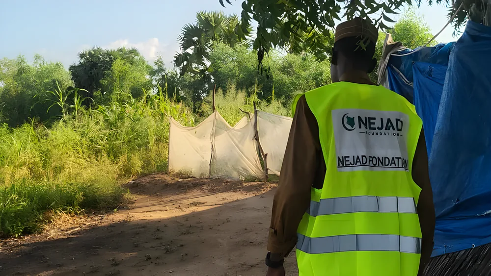 A NEJAD volunteer looks out over bushland and makeshift shelters